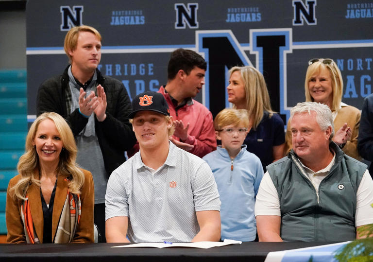 Jack Sanderson dons an Auburn baseball cap after signing to play baseball for the Tigers at Northridge High School Wednesday, Dec. 6, 2023. At left is his mother Kris Reddick and at right is his father, Barry.
