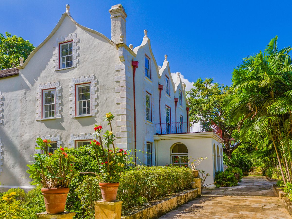 St. Nicholas Abbey in Barbados, showcasing the historic plantation house with its elegant architecture, surrounded by lush gardens and tall palm trees.