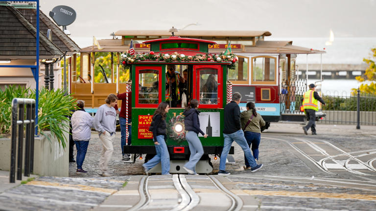 Passengers board a cable car decked out in holiday splendor as it prepares to depart the Fisherman's Wharf turnaround at Hyde and Beach Streets.