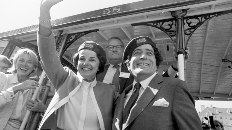 Mayor Dianne Feinstein waves to the crowd along with singer Tony Bennett, from California Street cable car No. 58 in front of the Fairmont Hotel in 1984. Bennett joined the mayor in relaunching the cable cars after a two-year overhaul of the system.