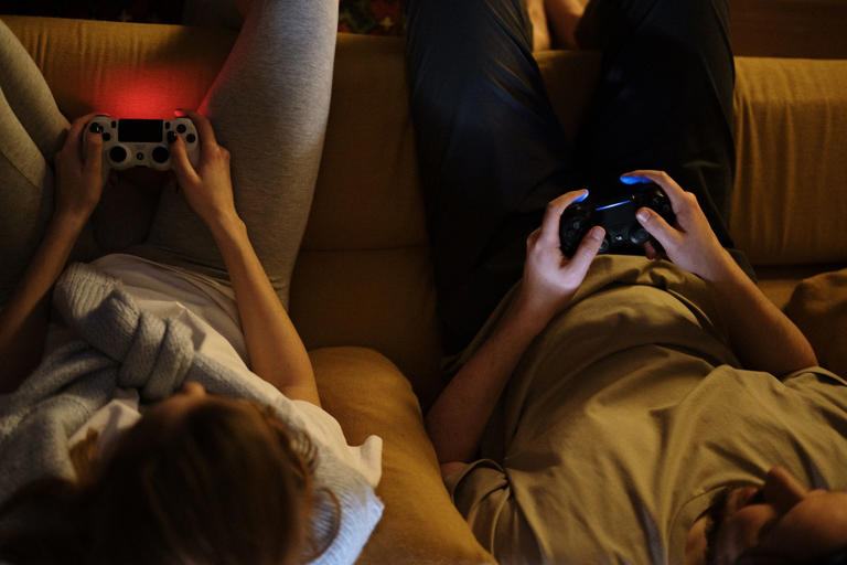 Couple on sofa with controllers in hands playing console game