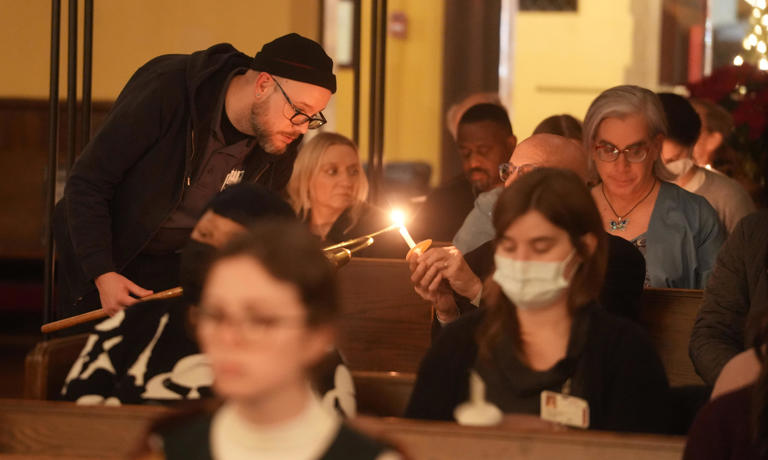 Dec 21, 2023; Columbus, Ohio: A man lights a candle for a participant in the Columbus Coalition For the Homeless 20th Annual Memorial Service for the 94 homeless people who died in Columbus in 2023. The service was held at Trinity Episcopal Church Downtown.