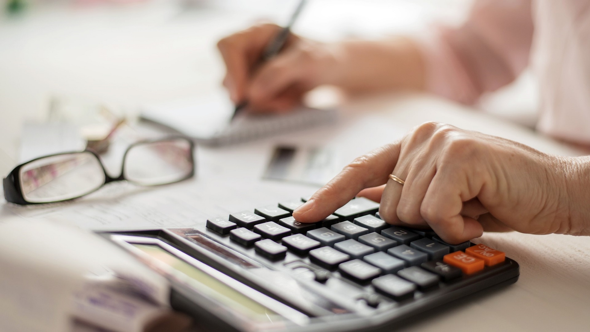 senior woman hands review finances budget calculator_iStock-1225117361