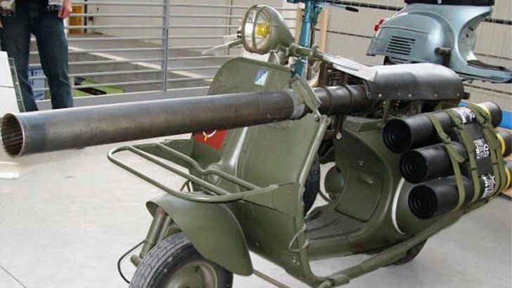 <p>The Vespa 150 TAP, produced in the 1950s by French vehicle manufacturer Ateliers de Construction de Motocycles et Automobiles, is a scooter that has been modified for use with paratroopers. It is outfitted with an M20 75 mm recoilless rifle, which is a lightweight anti-armor cannon. To transport ammunition, the scooter is accompanied by another motorbike.</p>