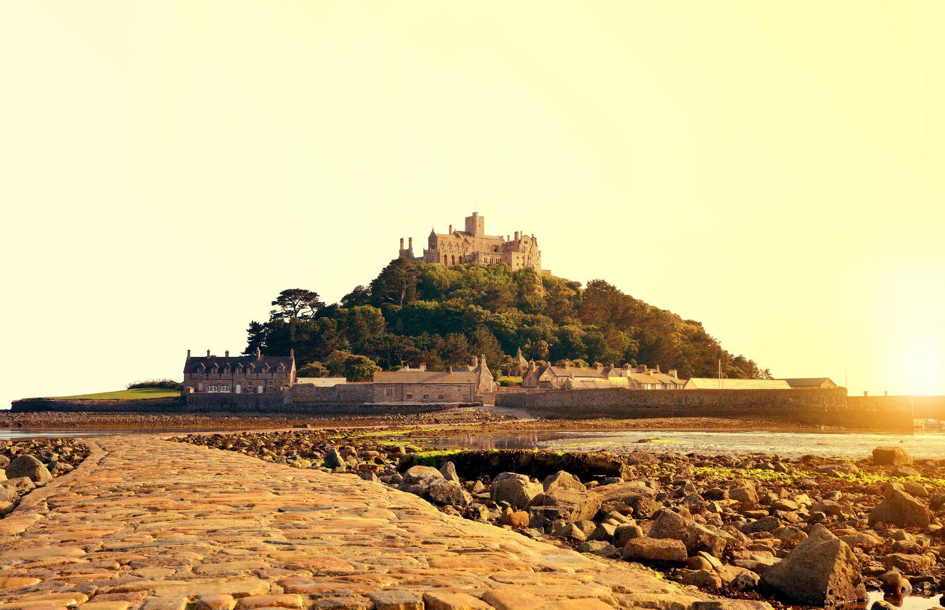 <p>Lying off Cornwall’s west coast, this <a href="https://www.stmichaelsmount.co.uk/">dramatic fortress</a> and island has been home to the St Aubyn family since the 17th century. It can only be reached by boat or by walking, at low tide, across a granite causeway from nearby Mount’s Bay in the town of Marazion, close to Penzance. With its spectacular old castle, beautiful gardens and breathtaking ocean views, the rocky island is a much-photographed jewel of the Cornish coastline.</p>