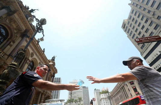 Agente da Defesa Civil distribui água a pedestres no centro de São Paulo durante a última onda de calor, em novembro Foto: Werther Santana/Estadão