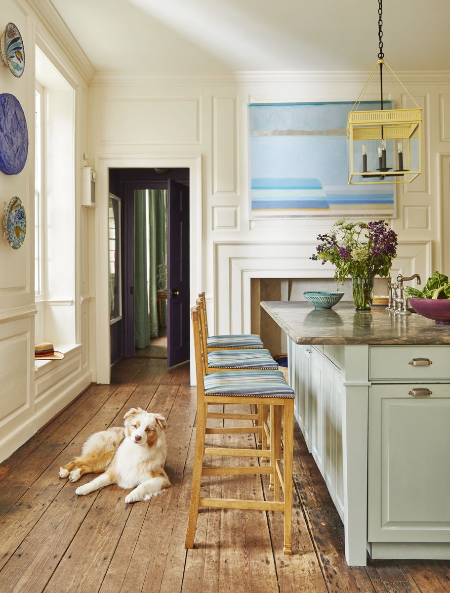 <p>The owners’ Australian shepherd, Bear, lounges on the kitchen’s wide plank flooring, smoothed over from centuries of use. Cushion fabric, <a href="https://www.perennialsfabrics.com/">Perennials</a>. Painting, Margaret Kennedy.</p>