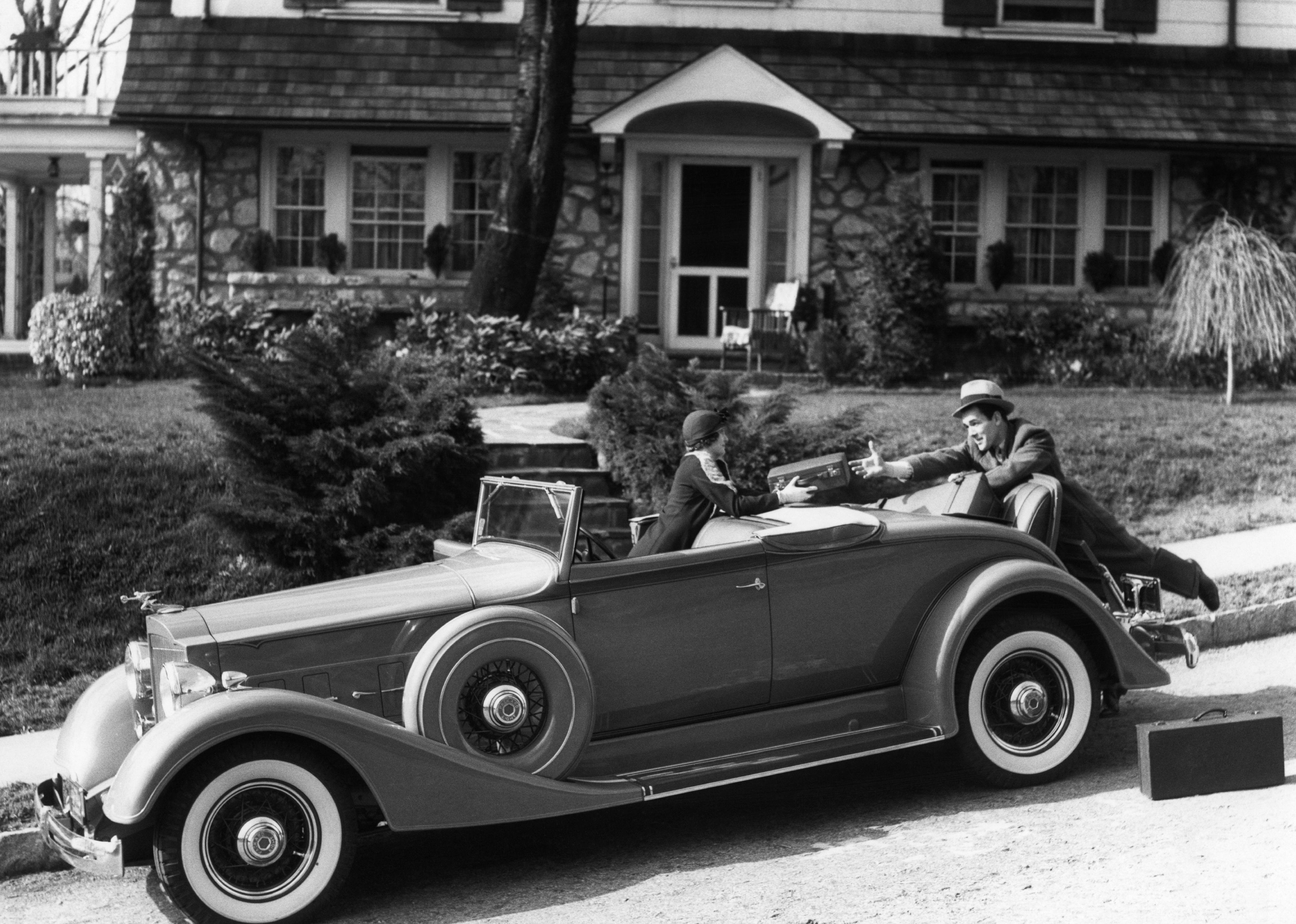 <p>A couple loads up their trunk with their luggage before setting out on a car trip in the early 1930s.</p>
