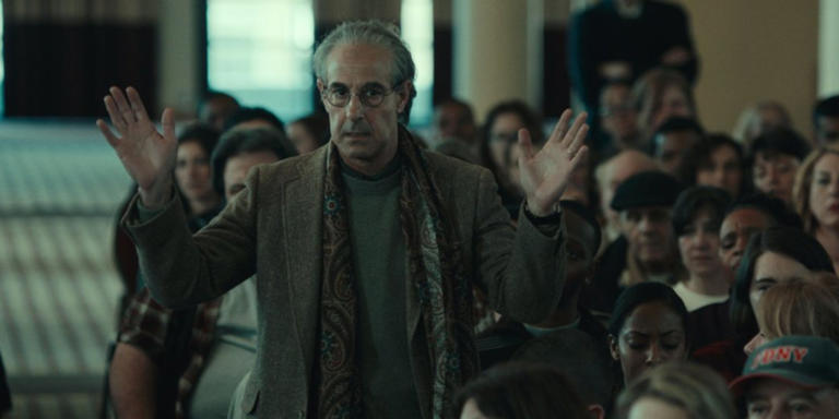 A character in Worth is holding his hands up. 