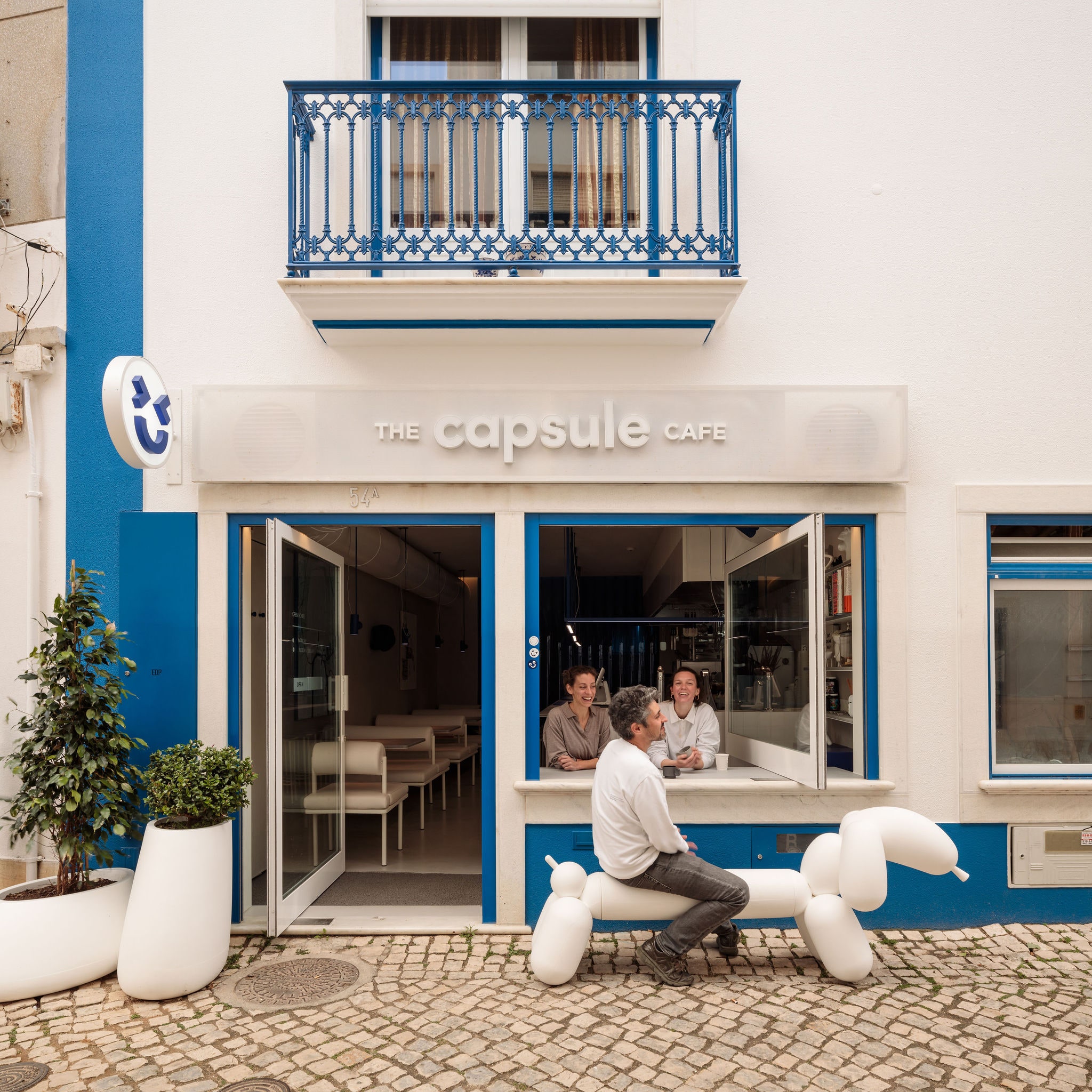 Atelier Réalité transformed a long commercial space into the Capsule Cafe, a unique coffee shop and restaurant in the fishing village of Ericeira, Portugal. The firm chose a blue-and-white palette as a nod to the sea, sky, and clouds, as well as the exteriors of local buildings. The plan of the narrow interior was inspired by a diner, with a sit-down counter along the open kitchen and a modern take on booths on the other side of the space. A bright blue plastic strip curtain conceals the bathroom and technical areas.<p>Sign up for our newsletter to get the latest in design, decorating, celebrity style, shopping, and more.</p><a href="https://www.architecturaldigest.com/newsletter/subscribe?sourceCode=msnsend">Sign Up Now</a>