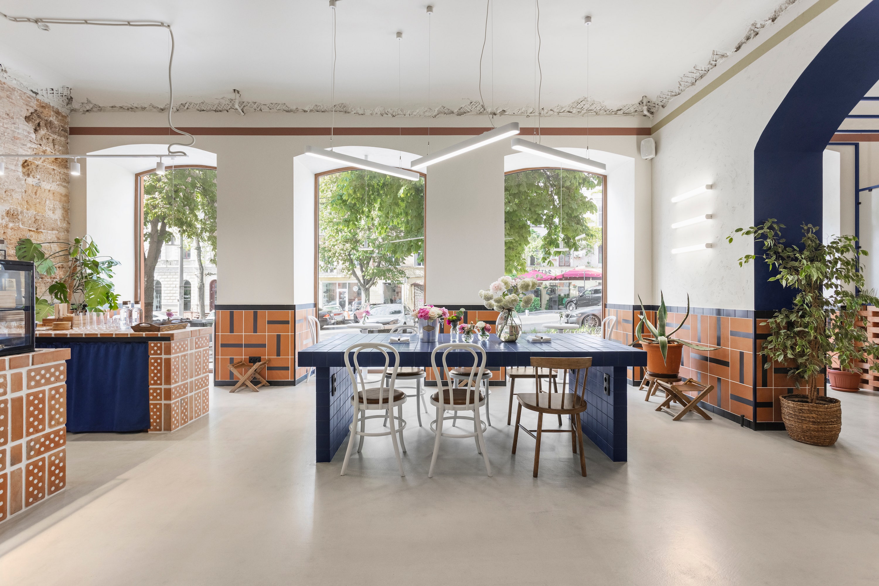 Bauhaus design inspired the interiors of <a href="https://www.instagram.com/godshot_coffee_odesa/?hl=en">Godshot Coffee</a> in Odesa, Ukraine. <a href="https://www.instagram.com/petrossjan_architecture/">Petrossjan Architecture Studio</a> used a bold but limited palette of vivid blue, white, and red brick and left the layout of the space open and preserved elements of the original architecture, such as the stone wall behind the bar. Hollow brick benches snake along the walls along with hand painted tiles, and a blue-tiled communal table was designed for freelancers in need of a workspace complete with built-in outlets.<p>Sign up for our newsletter to get the latest in design, decorating, celebrity style, shopping, and more.</p><a href="https://www.architecturaldigest.com/newsletter/subscribe?sourceCode=msnsend">Sign Up Now</a>