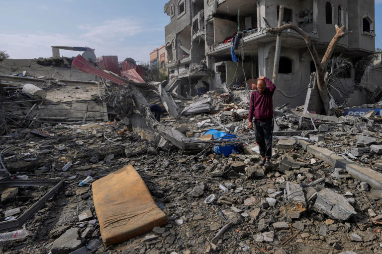 A man inspects the Al Nawasrah family’s destroyed building in Maghazi refugee camp, central Gaza (AP)