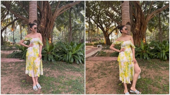 Another look from Rakul's holiday diaries shows the actor in a floral-printed midi dress. It features yellow flowers and green leaf patterns, a pleated tulle skirt, a tiered silhouette, a square neckline, a thigh-high slit, and a cinched waist. 