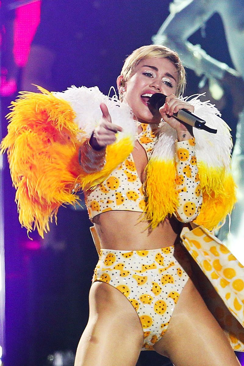 <p>Miley lives for an ab-baring costume, and this bright yellow stage look is no exception. There were feathers, rhinestones, and prints galore with this elaborate outfit. </p>