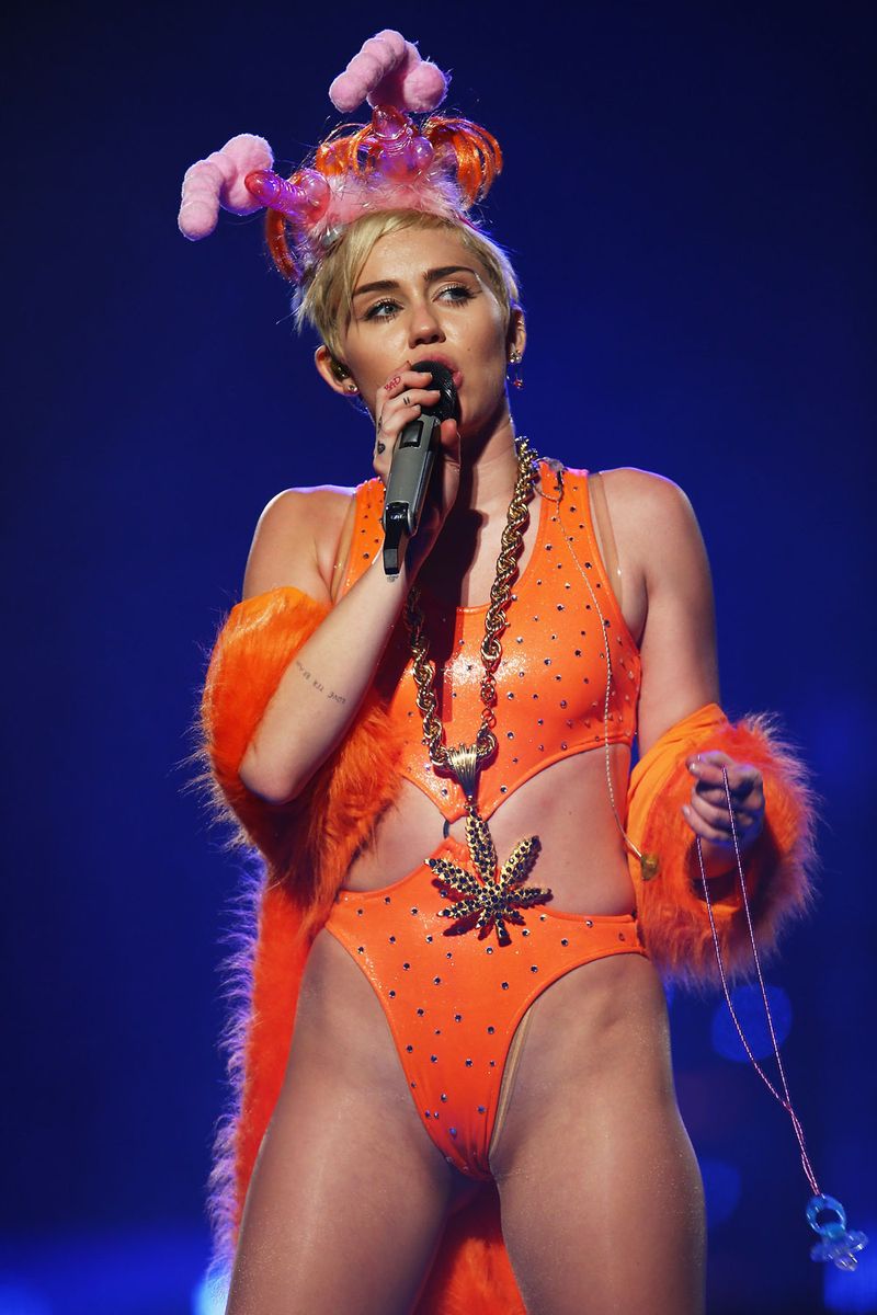 <p>Miley wearing a neon-orange one-piece, fuzzy shawl, questionable ears (those are penises, right?), and a gold marijuana leaf chain was peak <em>Bangerz</em>, TBH. Also, peep the baby pacifier on the chain. </p>