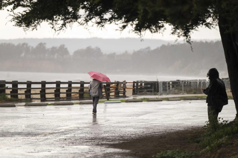 People walk through wet conditions along Seacliff State Beach in Aptos, Calif., Wednesday, Dec. 20, 2023. 