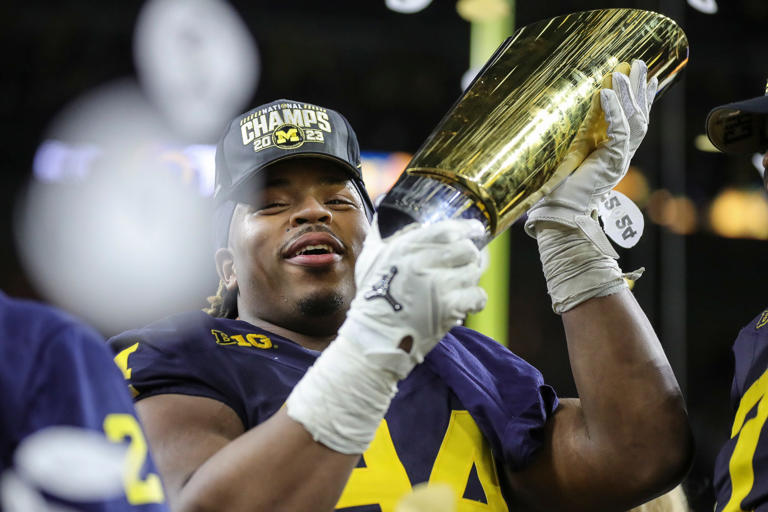 Michigan defensive lineman Kris Jenkins (94) picks up the trophy to celebrate the Wolverines' 34-13 win over Washington at the national championship game at NRG Stadium in Houston on Monday, Jan. 8, 2024.