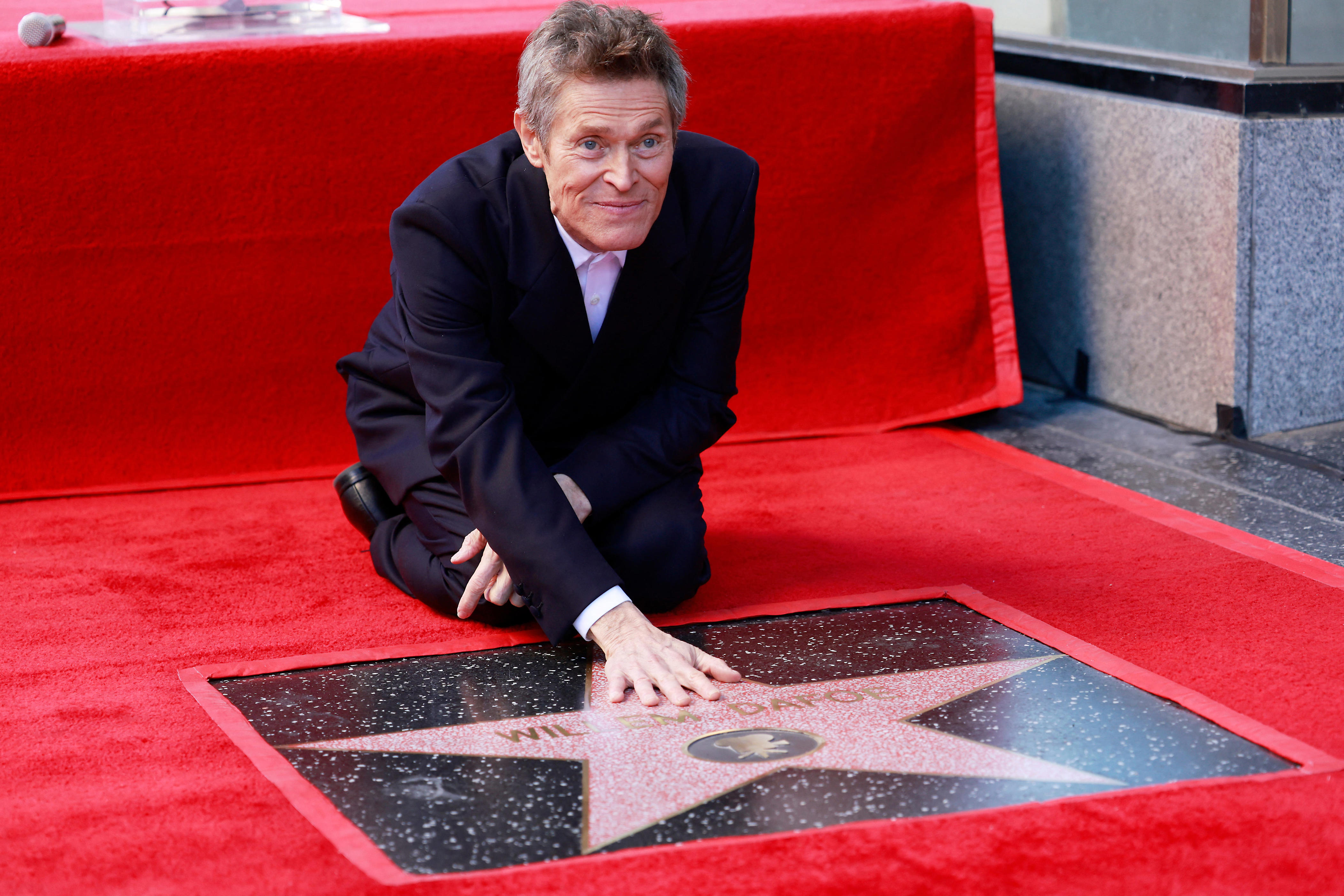 Willem Dafoe posed with his official stamp on the Hollywood Walk of Fame.