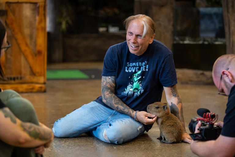 The Reptarium owner Brian Barczyk, center, talks with animal educator Amy Karjala, left, as he holds a Capybara, a new addition to his business, in Utica on June 23, 2023.