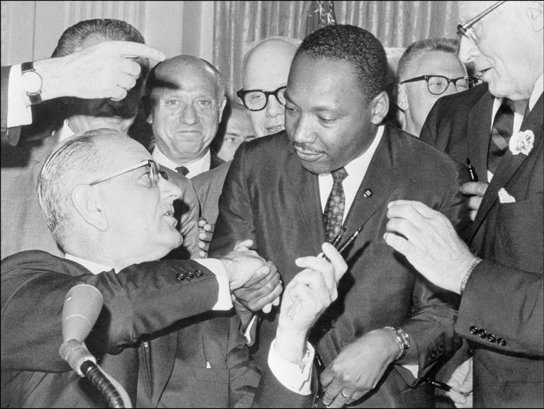 President Lyndon B. Johnson, left, shakes hands with Martin Luther King Jr. after signing the Civil Rights Act on July 3, 1964, at the White House.
