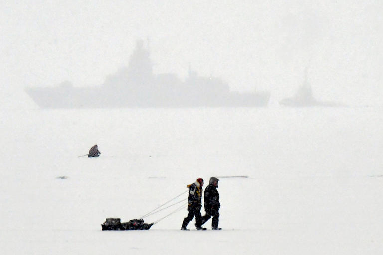 Fishermen walk on the ice-covered Gulf of Finland in front of a warship during a snowfall in Saint Petersburg on December 26, 2023. A power outage in the Russia’s Siberia region left almost half of Omsk city without power amid subzero temperatures.