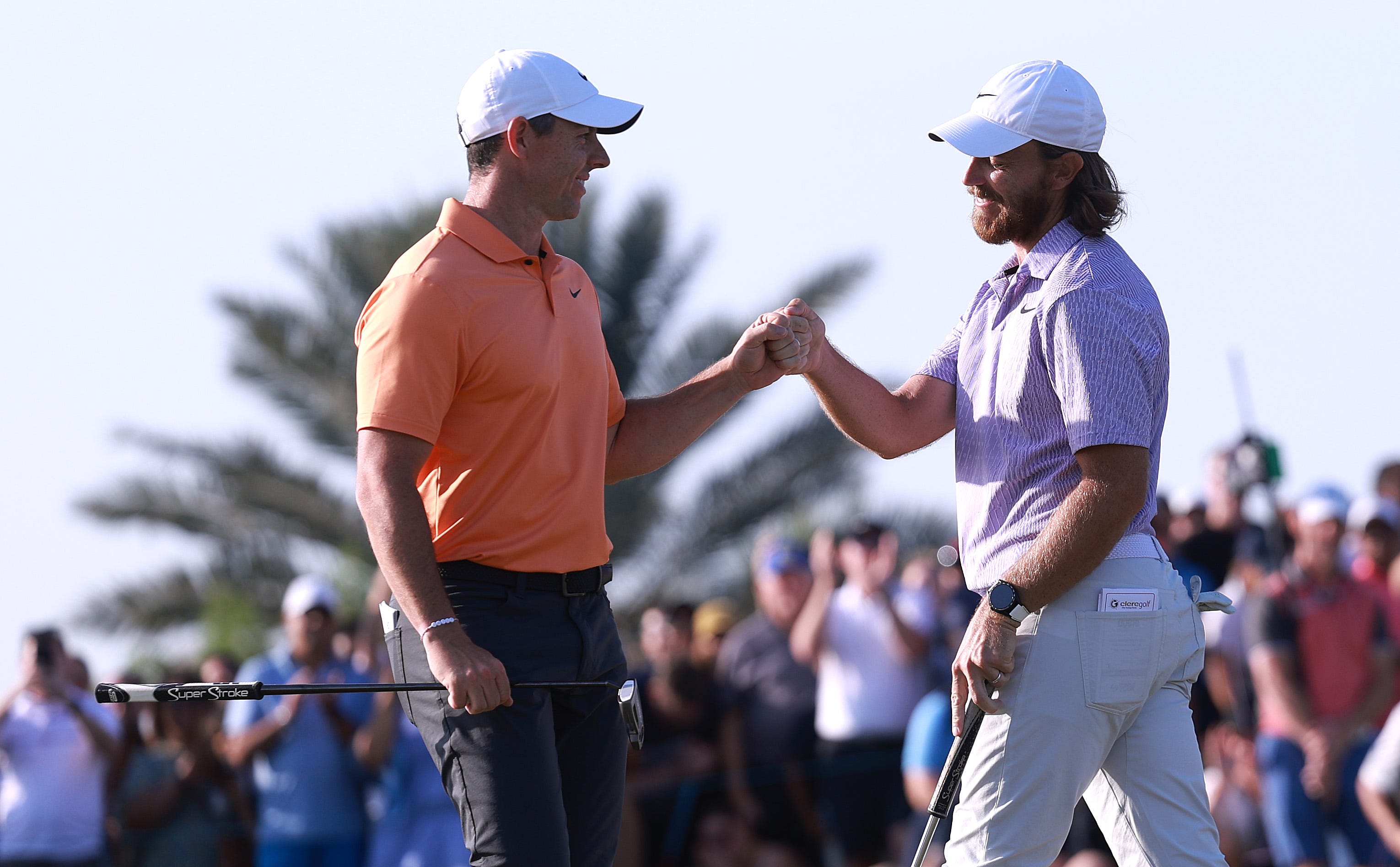 Rory McIlroy and Tommy Fleetwood bump fists on the 18th green as Fleetwood holes a putt to win the Dubai Invitational at Dubai Creek Golf and Yacht Club on January 14, 2024 in Dubai, United Arab Emirates. (Photo by Warren Little/Getty Images)