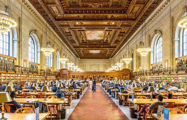 a large room with tables and people with new york public library in the background