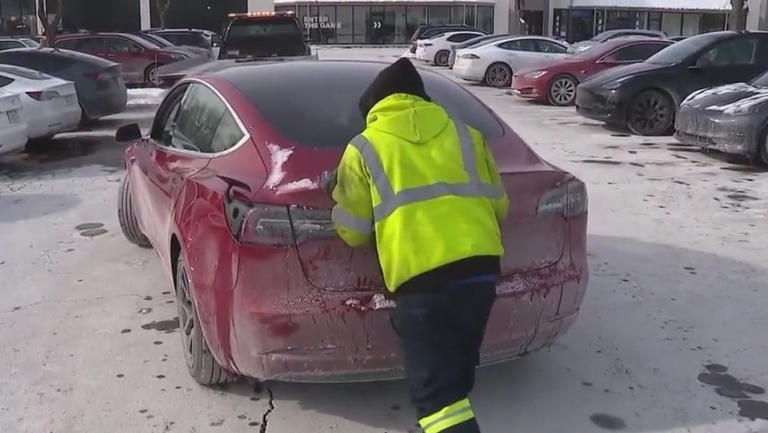 Someone pushes a Tesla at a Chicago-area vehicle charging station where many of the electric vehicles have been forced to sit amid freezing temperatures. Many of the vehicles failed to charge at stations around Chicago amid the cold weather. WFLD