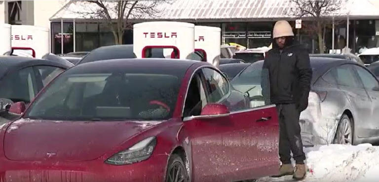 A visibly frustrated man stands near a Tesla that failed to charge at a Chicago-area charging station on Monday. WFLD