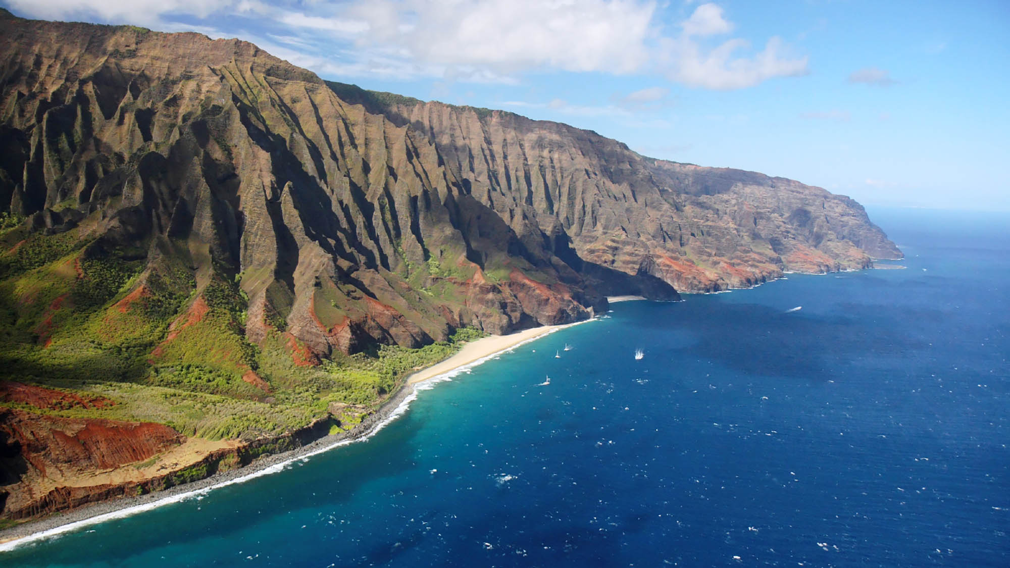 <p><span><span><span><span><span><span>Stretching along the northwest shore of Kauai, the NaPali Coast in Hawaii is a gorgeous blend of towering sea cliffs, green valleys, and pristine beaches. The rough terrain appears much like it did centuries ago when Hawaiian villages prospered.</span></span></span></span></span></span></p>  <p><span><span><span><span><span><span>The Kalalau Trail, a challenging 11-mile trek, unveils panoramic views of this coastal wonder. Verdant valleys, like Hanakapiai and Kalalau, punctuate the coastline, providing sheltered havens for diverse flora and fauna. Hidden sea caves and cascading waterfalls add an enchanting touch to the already surreal landscape.</span></span></span></span></span></span></p>  <p><span><span><span><span><span><span>One of the best ways to experience the NaPali Coast is by boat, allowing visitors to witness the sea cliffs rising dramatically from the ocean, revealing hidden valleys inaccessible by land. As the sun sets, the cliffs glow with hues of amber and gold, casting an aura over the rugged coastline. Visitors can see this 17-mile coastline by boat or by air. There are also kayaking trips that allow visitors to see the cliffs up close.</span></span></span></span></span></span></p>