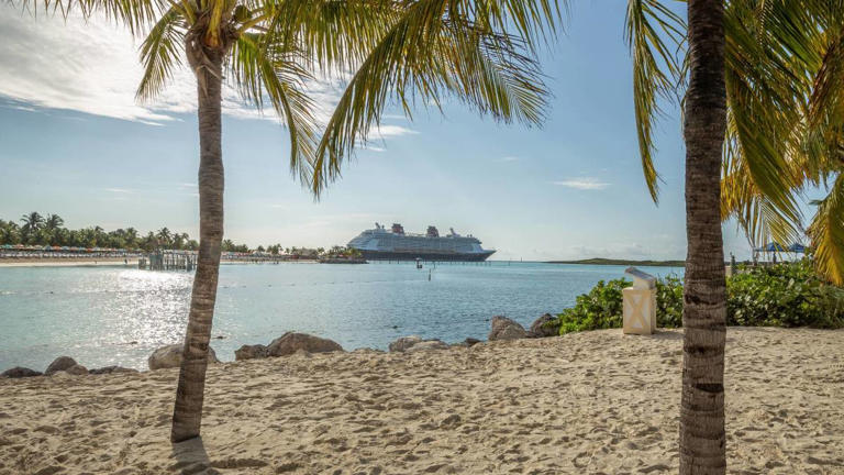 A sandy beach is seen with a cruise ship in the distance on Castaway Cay in the Bahamas. -lead