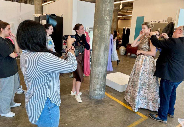 Syracuse University fashion design students crowd around Juli Boeheim as their professor, Jeff Mayer, makes alterations on a dress she will wear this weekend at the 25th and likely final Basket Ball. April 23, 2024
