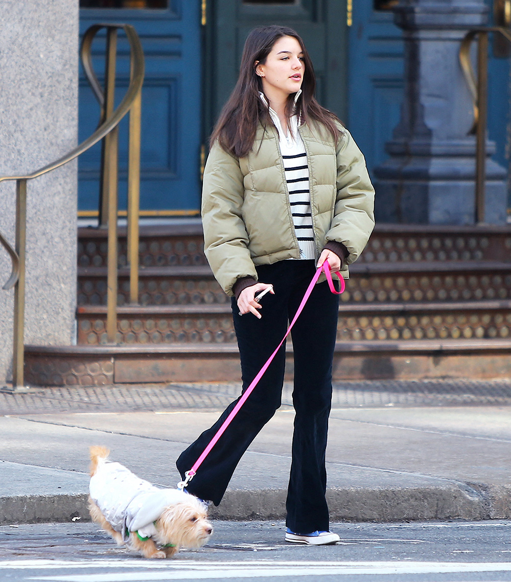 <p>Suri Cruise walks her new puppy with a friend in Soho, New York City on Mar. 14, 2022. She looked cool in an olive puffer jacket, striped sweater and flared pants.</p>