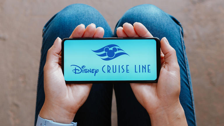 woman holds disney cruise line logo smartphone_BLU_A71022552