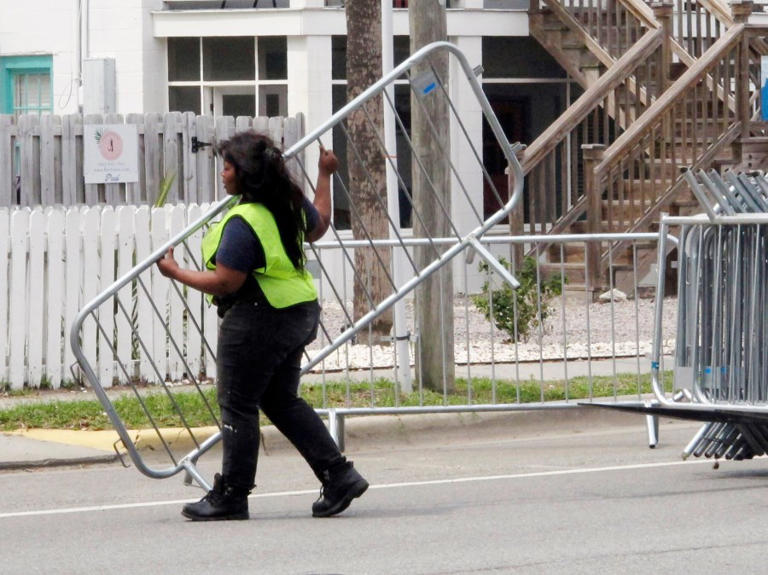 A worker places a section of metal barricade along a main road on Tybee Island, Ga., on Tuesday, April 16, 2024, a few days ahead of the weekend beach party known as Orange Crush. Black college students started the spring bash at Georgia’s largest public beach more than 30 years ago. Tybee Island officials are blocking roads and parking spaces and bringing in about 100 extra police officers for the party this weekend, saying record crowds last year proved unruly and dangerous. (AP Photo/Russ Bynum)