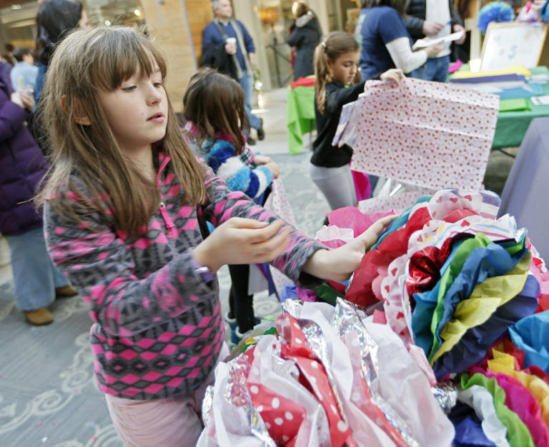 Emma Wrench, 8, of Granville adds a colorful creation to a growing pile of donations during a Cynthia's Flowers project at the Worthington Farmers Market.