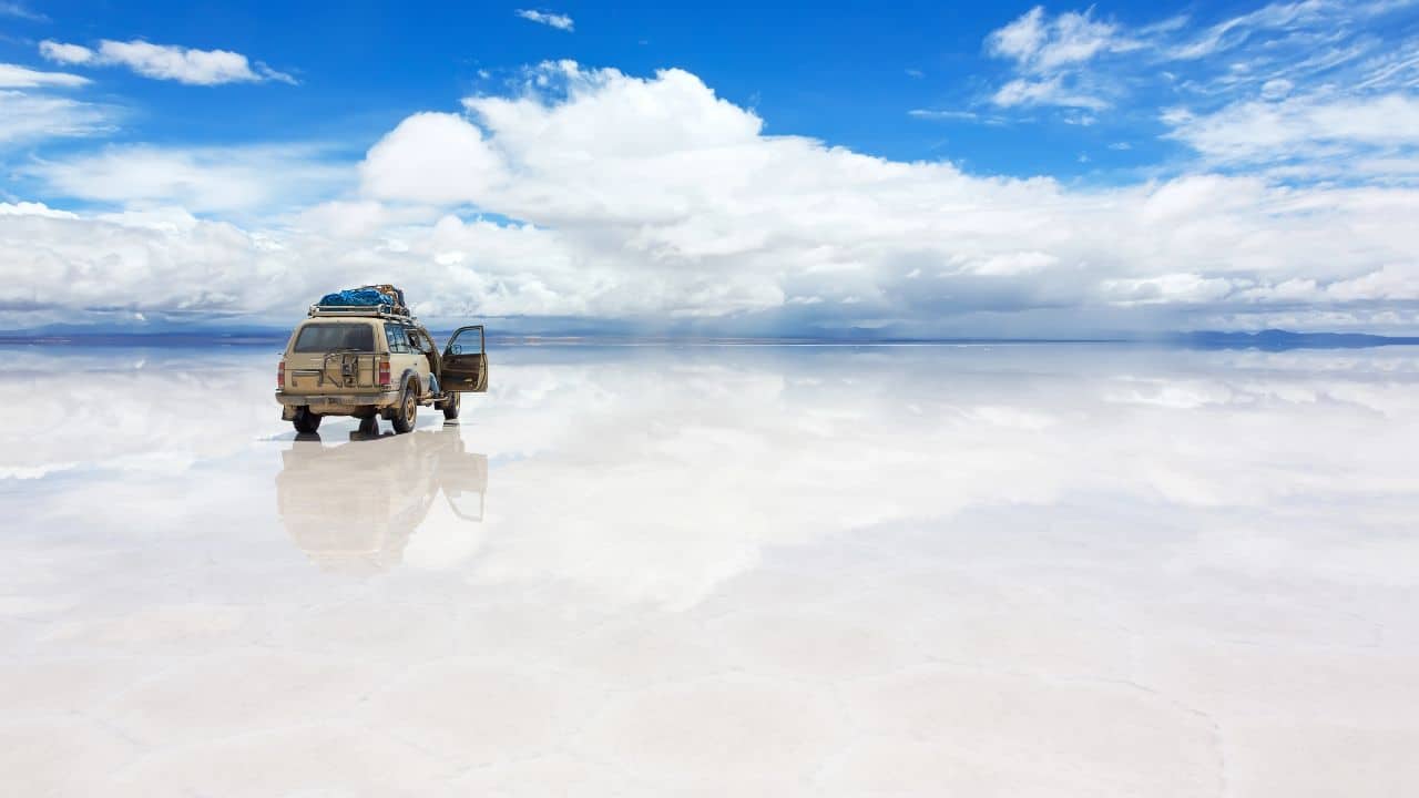<p>Located in southwest Bolivia, <a href="https://explorersaway.com/salar-de-uyuni-bolivia-salt-flats/">Salar de Uyuni</a> is the largest salt flat in the world, covering over 4,086 square miles. During the rainy season, a thin layer of water transforms the flat into a giant mirror, reflecting the sky in a breathtaking display of symmetry. The surreal landscape of endless white stretches to the horizon, creating a truly unique and mesmerizing experience; even better are the midnight tours, when the stars are reflected on the water.</p>