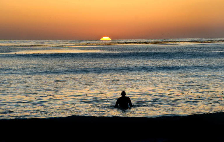 A surfer watches the sun set from the ocean at Carmel-by-the-Sea in September 2010.