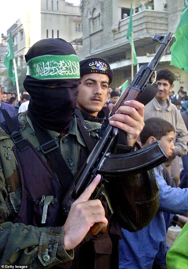 A masked Hamas militant, holding an AK-47 rifle and wearing a headband that reads 'No gods only one God, Mohammed is Prophet of Allah' in Gaza City in 2002