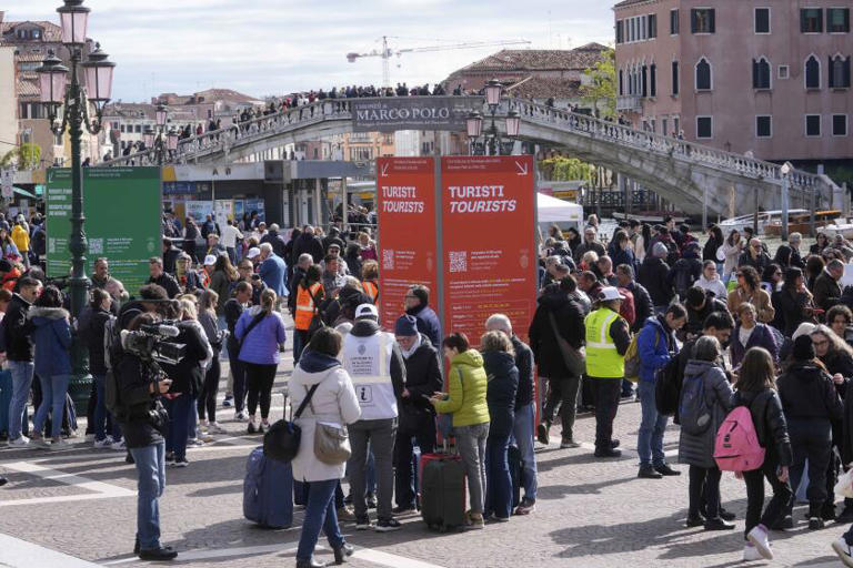 Stewards check tourists QR code access outside the main train station in Venice, Italy, on Thursday. The fragile lagoon city of Venice begins a pilot program Thursday to charge day-trippers a 5-euro entry fee that authorities hope will discourage tourists from arriving on peak days. ((Luca Bruno / Associated Press))