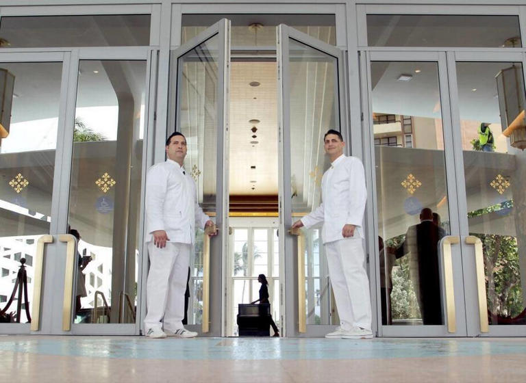 Porters Yandy Lopez, left, 41, and Felix Alpizar, 38, hold the door for guests as they enter the signature lobby space of the Faena Hotel which opened in 2015