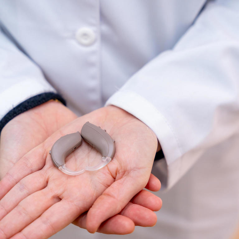 Close-up of hearing aid device in hands of a doctor specialist