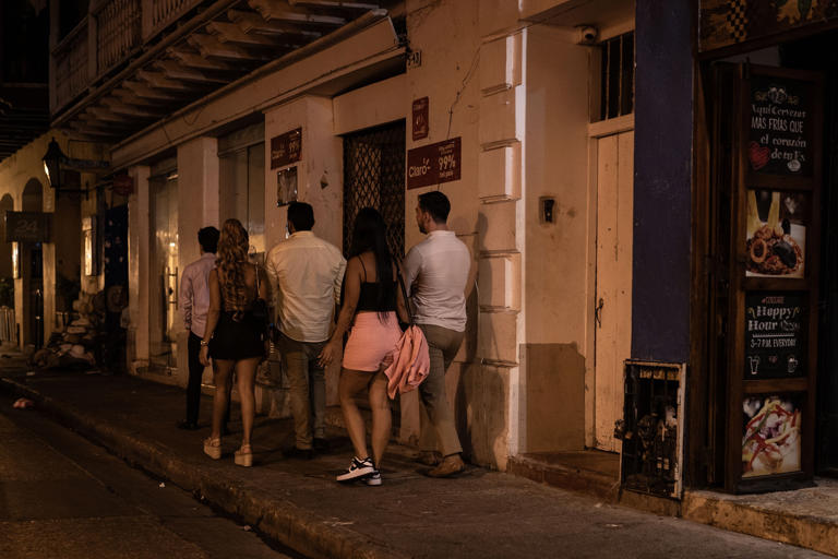 Tourists walk with local women in the historic center of Cartagena, February 22, 2024.
