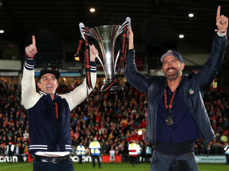 Rob McElhenney (left) and Ryan Reynolds (right) celebrate Wrexham's promotion to League Two in April 2023