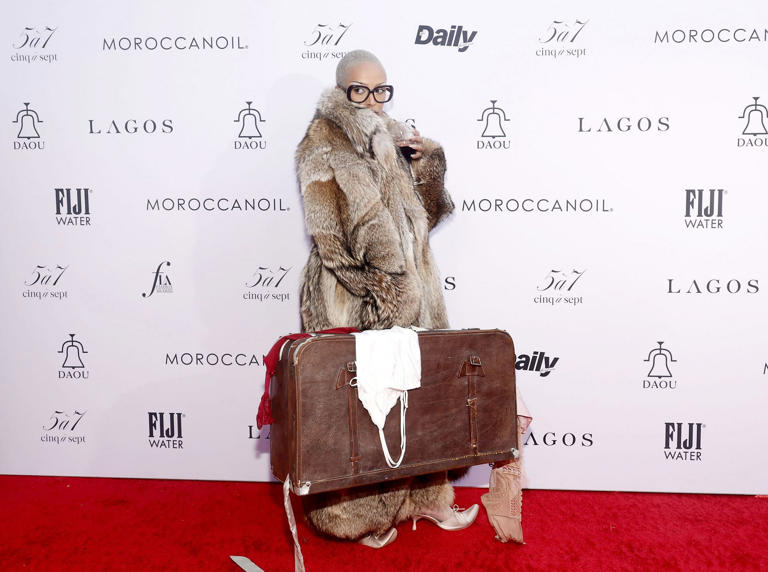Doja Cat carries glass of wine and suitcase on red carpet at 2024 Daily Front Row's Fashion Los Angeles Awards