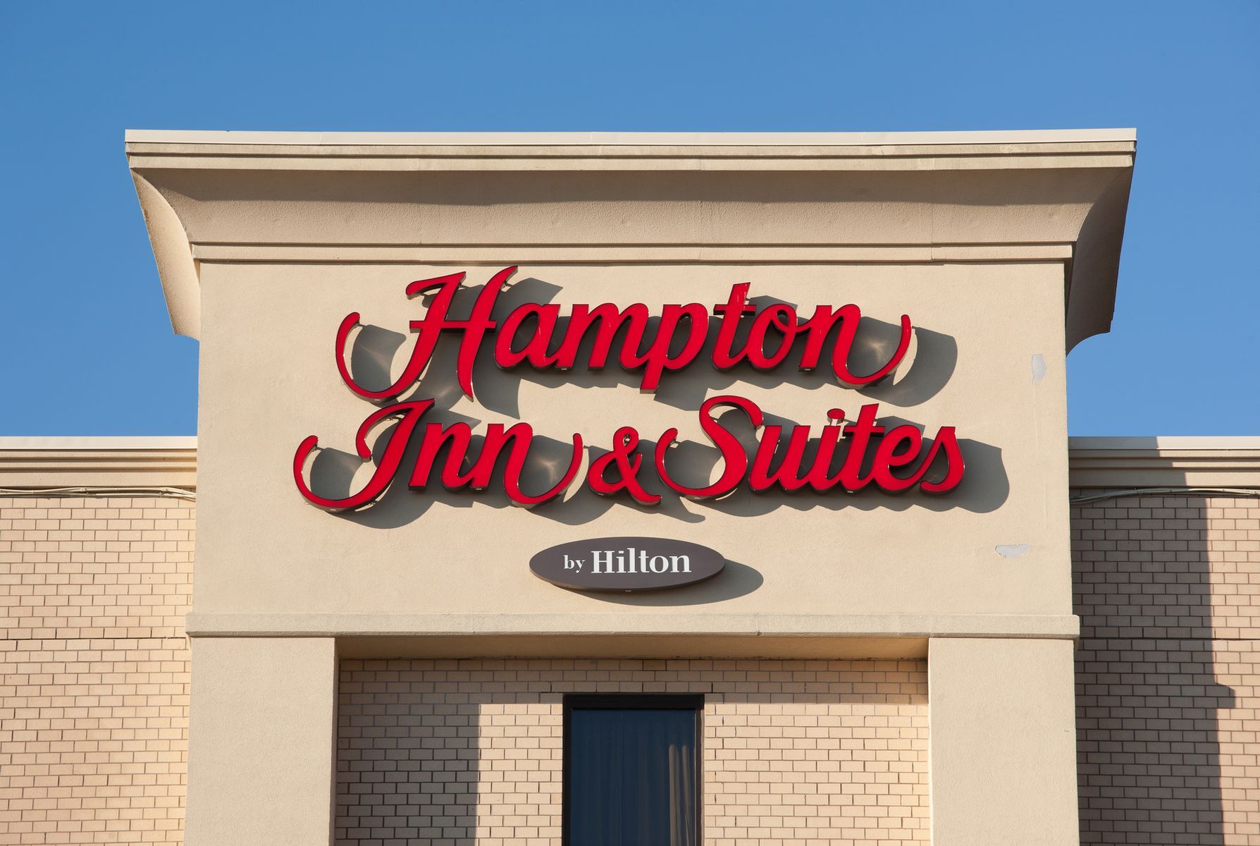 <p>Originally, Hampton was part of the Holiday Inn family before being <a href="https://ir.hilton.com/~/media/Files/H/Hilton-Worldwide-IR-V3/annual-report/1999-Annual-Report-Page-3-Removed.pdf">purchased by Hilton</a> in 1999 for US$3.7 billion. The organization now operates as a middle-market offering from parent company Hilton Worldwide, generally known for their more extravagant hotels. As an example of the differences, Hilton hotels typically offer luxury onsite restaurants, while Hampton hotels instead feed their guests with complimentary breakfasts—a cozy service that Hilton doesn’t offer within the United States.</p>