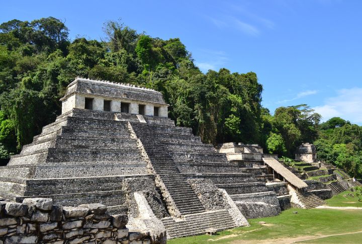 <p>The Temple of the Inscriptions is Palenque’s largest Mesoamerican stepped pyramid structure. It was dedicated to King Pakal, one of the most powerful rulers of Palenque, who reigned for nearly 70 years in the 7th century AD. Its most fascinating aspect is its hidden burial chamber. Unlike other pyramids where the tomb might be at the top, the Temple of the Inscriptions’ chamber lies beneath it. Archaeologists only discovered the entrance to the tomb in 1952 after noticing movable floor slabs. Archaeologists found a richly decorated sarcophagus inside the tomb containing King Pakal’s remains. The sarcophagus lid depicts the king adorned with royal garb and emerging from the jaws of a monster, possibly symbolizing rebirth or transformation.</p>