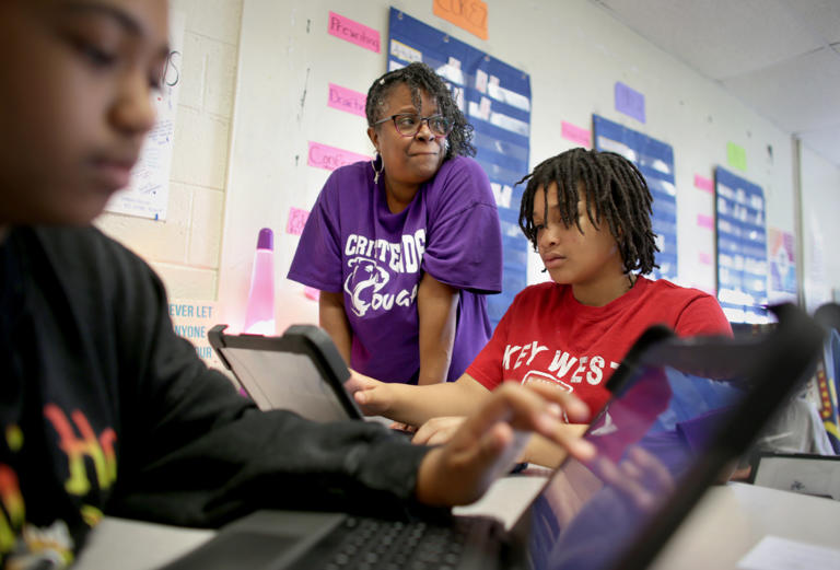 Chanda Woods works with her Crittenden Middle School sixth-grade English students, including Tyanna Thomas, 12, left, and Tylin Scott, 11, on Friday, April 26, 2024. Woods was named a regional teacher of the year and is in the running for the state title.