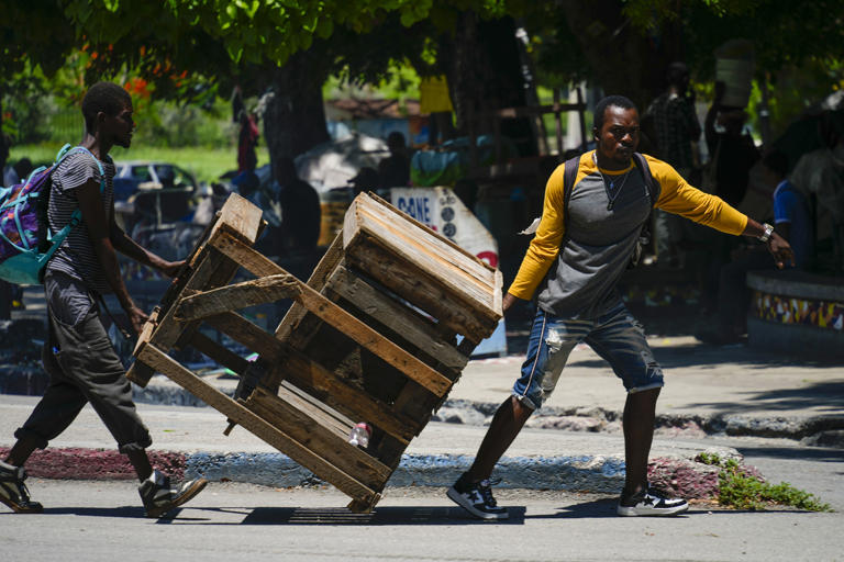 Street vendors move their booth after gunshots broke out near the National Palace in Port-au-Prince, Haiti, Tuesday, April 30, 2024. (AP Photo/Ramon Espinosa)