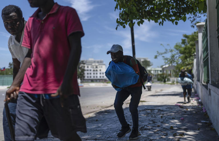 CORRECTS DAY - People run for cover as shots ring out near the National Palace in Port-au-Prince, Haiti, Tuesday, April 30, 2024. (AP Photo/Ramon Espinosa)